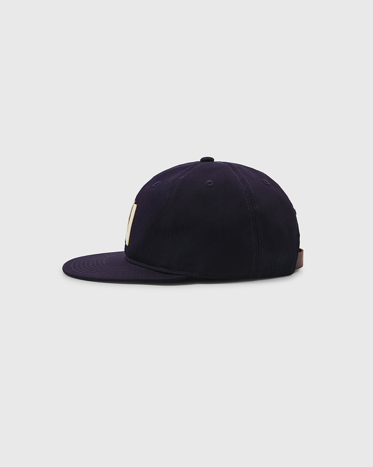 The Ebbets Field Brooklyn Eagles Cotton Twill Ballcap in navy is shown from the side on a plain light gray background, with a small part of a beige letter visible on the front panel.