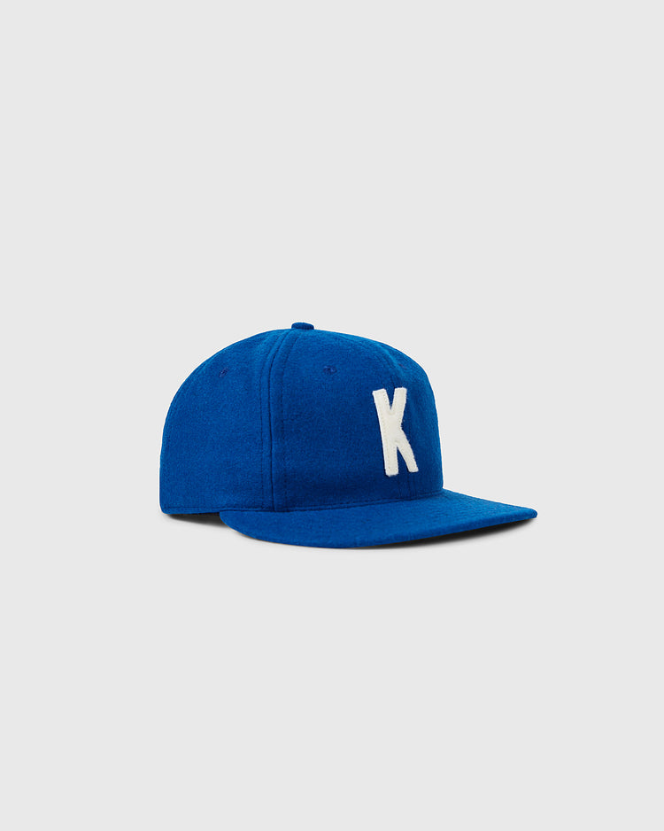 The EFF University of Kentucky 1964 Vintage Ballcap is a blue cap with a white K on the front, inspired by the original 1964 design, shown against a light gray background.