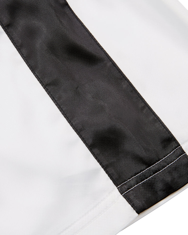 Close-up of Ebbets Field Muhammad Ali Vintage Inspired Boxing Trunks: smooth white fabric with a wide black stripe and visible white stitching, evoking the iconic look from the Thrilla in Manila 50th anniversary.