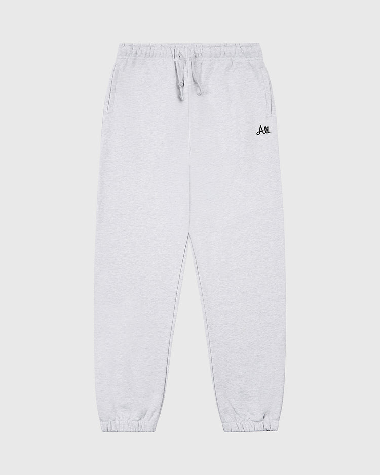 Ebbets Field Muhammad Ali Embroidered Heavyweight Cotton Terry Sweatpants in light gray feature an elastic waistband, drawstring, side pockets, elastic cuffs, and a black “Ali” logo on the left thigh. Inspired by classic boxing training gear.