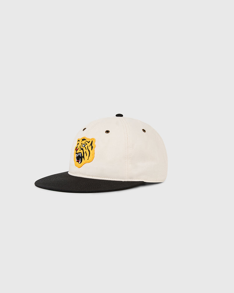 The Ebbets Field Osaka Tigers Cotton Twill Ballcap features a cream body, black brim, and yellow embroidered roaring tiger face on the front, inspired by the classic Japanese team cap and shown on a light gray background.