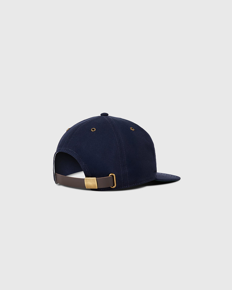 The Sanke Atoms Cotton Twill Ballcap by Ebbets Field is shown from the back in navy blue, featuring a brown adjustable strap with a gold clasp and metal eyelets, set against a light gray background.