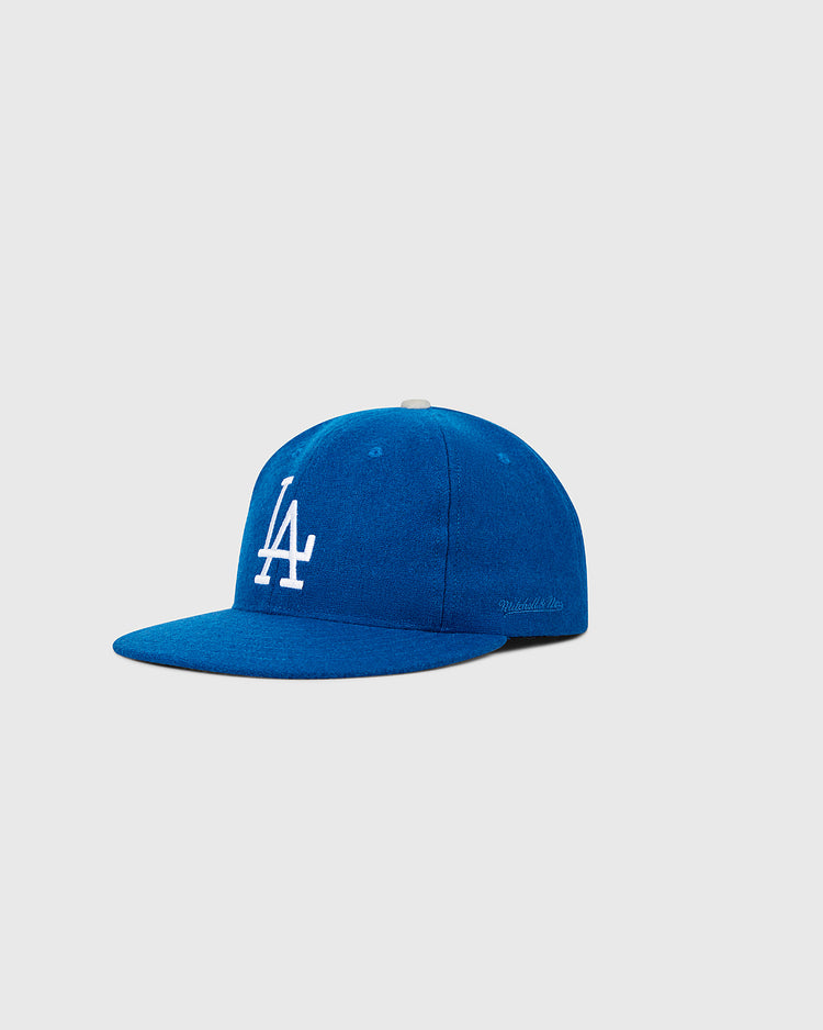 The Ebbets Field Los Angeles Dodgers 1958 MLB Authentic Wool Ballcap is a blue cap with a flat brim and white LA initials, inspired by the original on-field design, shown against a plain light gray background.