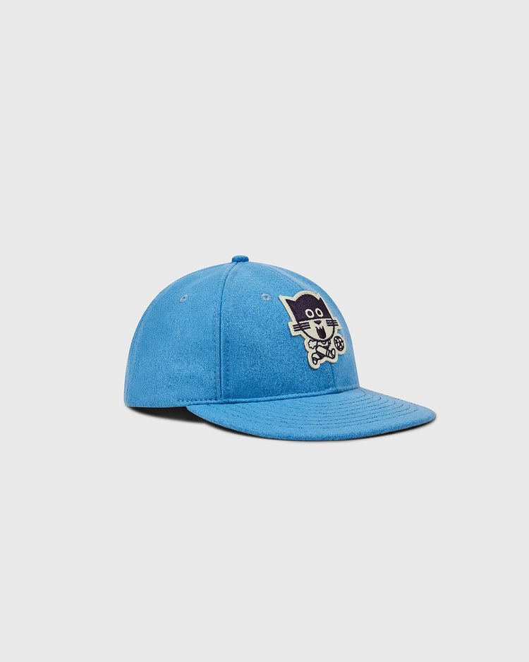 The EFF Chicago Cats 1976 Authentic Wool Ballcap is a blue flat-brim cap with a cartoon cat riding a bicycle embroidered on the front, inspired by the 1979 Chicago Cats soccer team logo. The background is plain white.