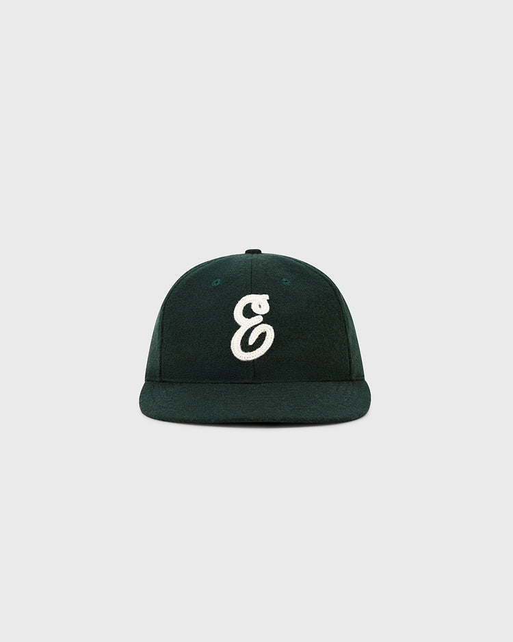 The Ebbets Felt 'E' Wool Ballcap by Ebbets Field is a dark green vintage-style wool cap, featuring a white embroidered “E” on the front, shown against a plain light gray background.