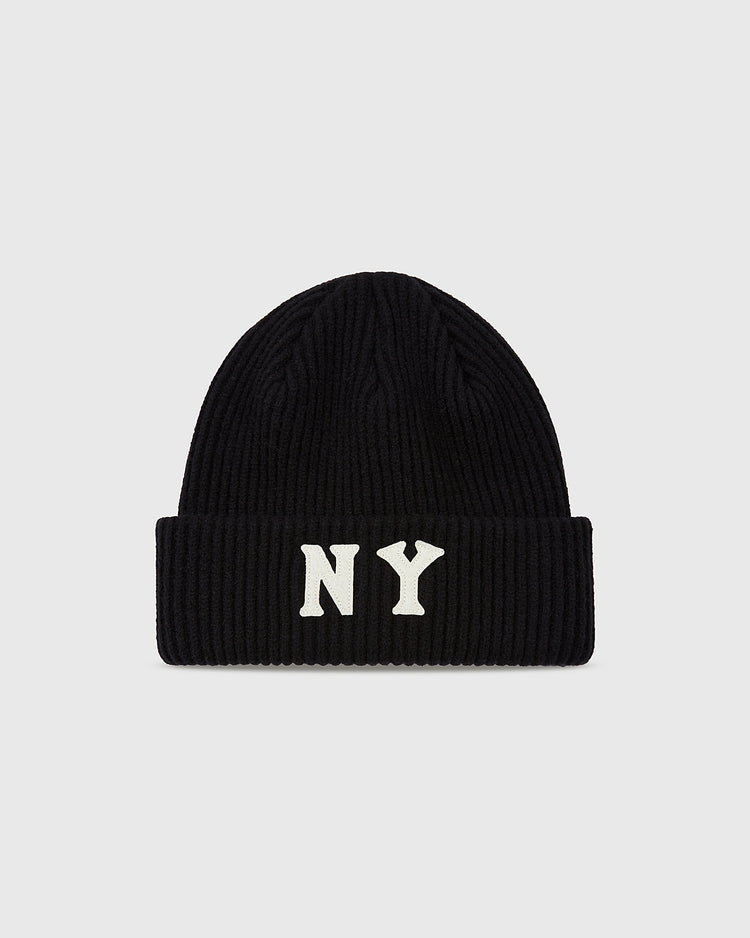 The Ebbets Field New York Black Yankees Felt Logo Ribbed Beanie is a black knit hat with a folded brim and bold white NY letters on the front, shown on a plain light gray background.