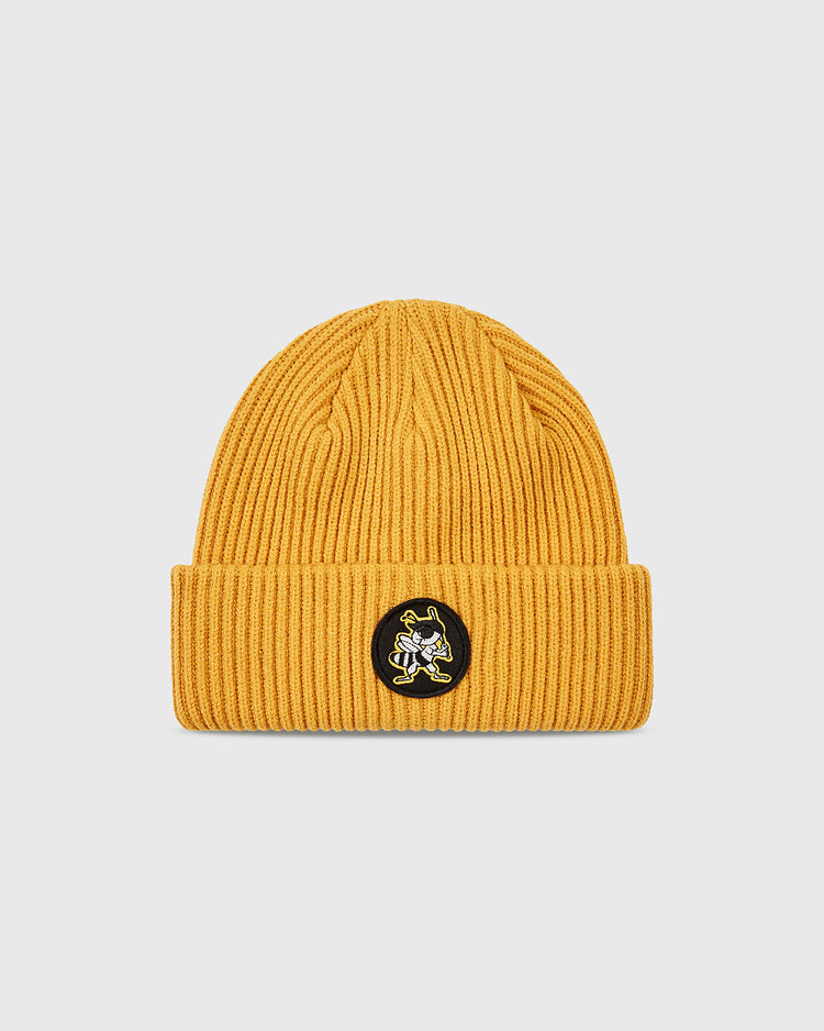 The Ebbets Field Salt Lake Bees Patch Logo Ribbed Beanie in mustard yellow features a folded brim and a circular black patch with an embroidered cartoon bee, celebrating the Salt Lake City Bees of the Pacific Coast League.