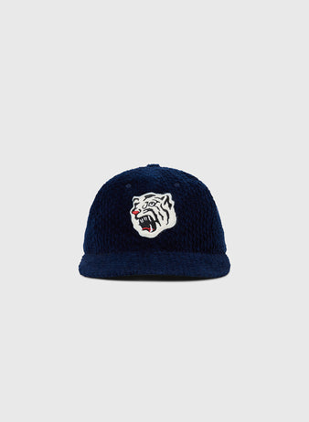 The Osaka Tigers Japanese Indigo Corduroy Ballcap by Ebbets Field features indigo-dyed corduroy and a white tiger head with open mouth and red tongue, inspired by the Osaka Tigers, on a light gray background.