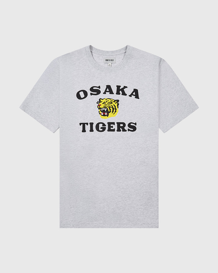 The Ebbets Field Osaka Tigers Short Sleeve Graphic Tee is a light gray t-shirt with bold black text and a yellow tiger head graphic on the front, inspired by Japanese baseball and Koshien Field legends.