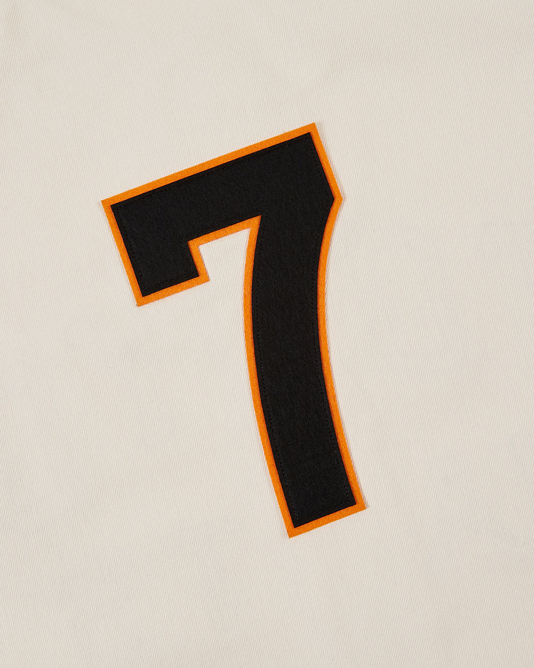 The Ebbets Field Tokyo Giants 1953 Cotton Twill Baseball Jersey features a black number 7 with an orange outline on white or cream cotton twill, reminiscent of a vintage baseball jersey.