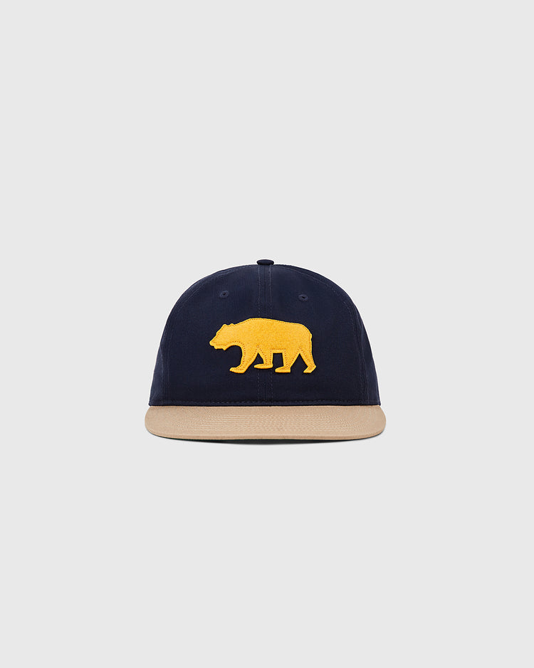 The Ebbets Field Mission Bears Cotton Twill Ballcap, in navy with a beige brim and yellow bear emblem inspired by the 1926 team, is displayed on a plain light gray background.