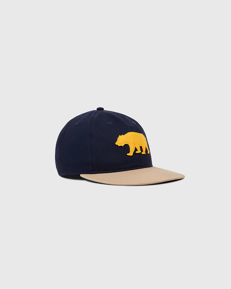 The Ebbets Field Mission Bears Cotton Twill Ballcap is a navy vintage cap with a tan brim and bold yellow bear graphic, inspired by Bay Area baseball, shown on a plain light gray background.