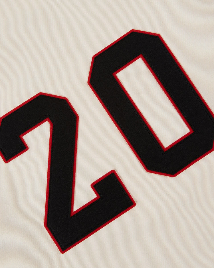 A close-up of the Ebbets Field Birmingham Black Barons Cotton Twill Jersey shows cream fabric with a bold black number 20 outlined in red, echoing the style of historic team jerseys.