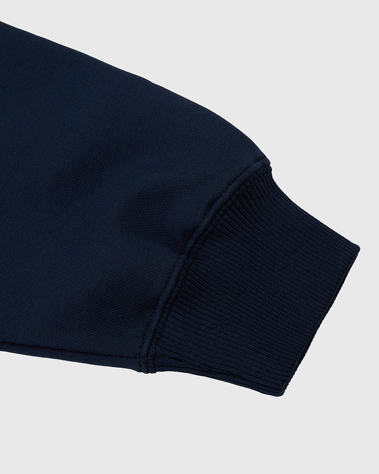 A close-up of the cuff on the Ebbets Field Hiroshima Carp Heavyweight Cotton Terry Full-Zip Hoodie in dark navy blue, highlighting the ribbed sleeve against a light gray background.
