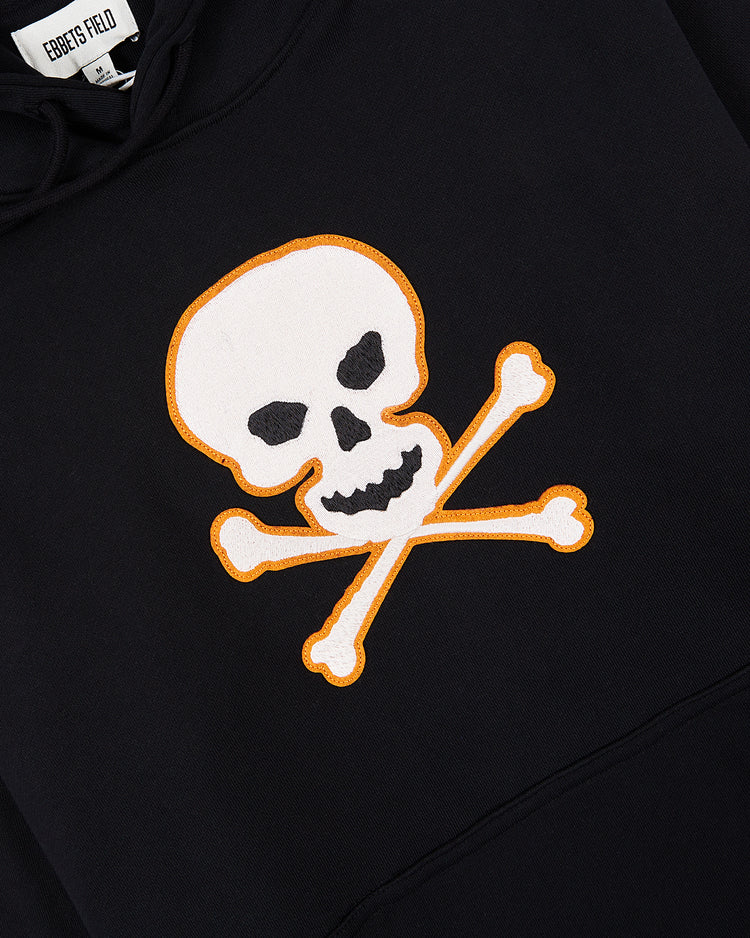 The Sioux City Ghosts 'Skull and Bones' Heavyweight Cotton Terry Pullover Hoodie by Ebbets Field features a bold white skull and crossbones with orange outline, honoring the legendary fast-pitch softball team.