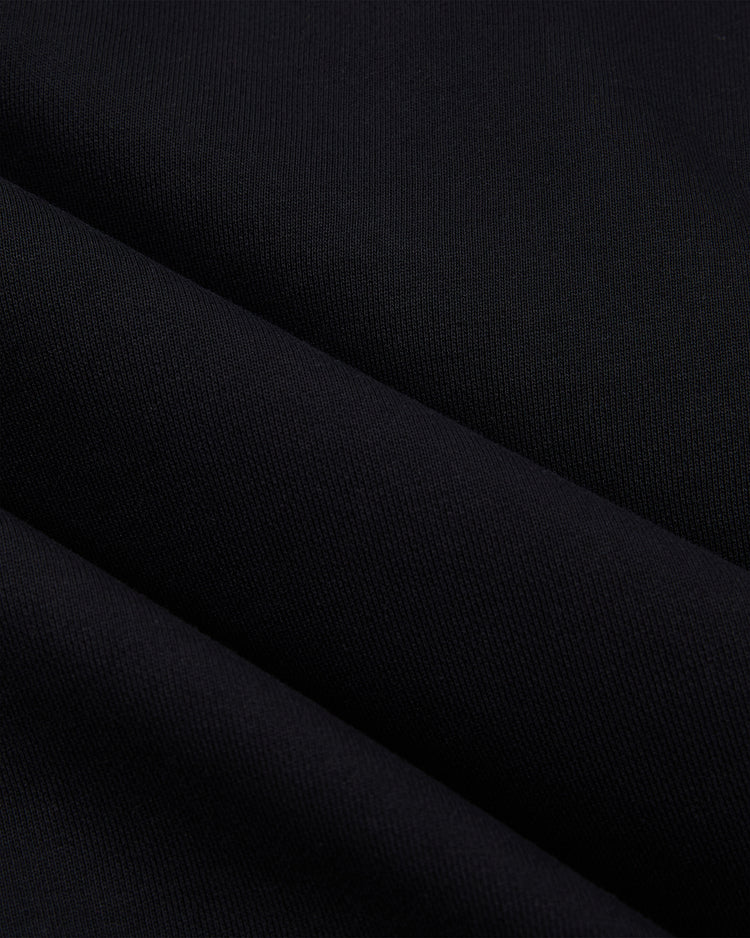 Close-up of smooth, heavyweight black cotton terry with subtle diagonal folds and a soft texture—ideal for the Ebbets Field Sioux City Ghosts 'Skull and Bones' Pullover Hoodie.