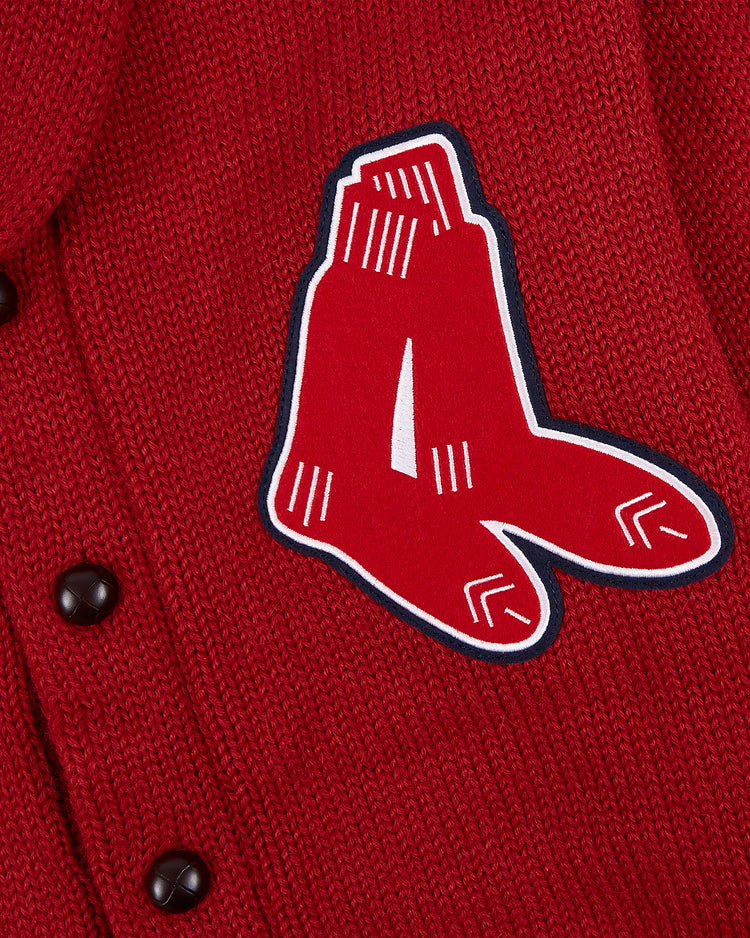 Close-up of the EFF Boston Red Sox 1924-1960 Wool Shawl Collar Sweater, featuring red knit fabric, black buttons, and a patch with the hanging socks logo outlined in white and black.