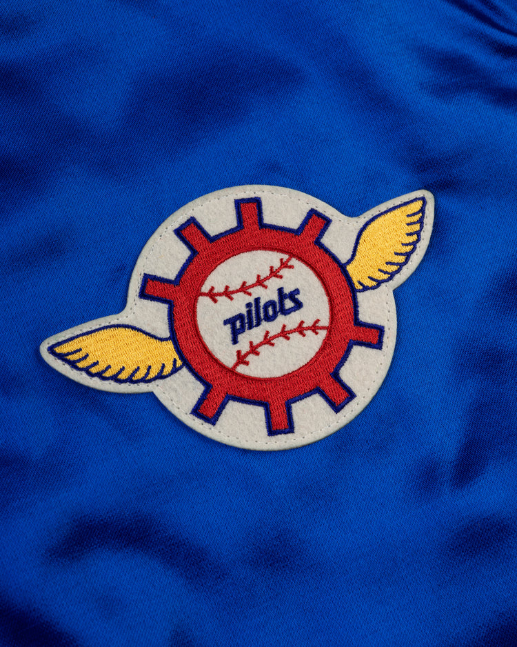 The EFF Seattle Pilots 1969 Authentic All Satin Varsity Jacket features blue fabric and a patch with a red gear, baseball with pilots, and yellow wings—ideal for fans and perfect for any replica team jacket.