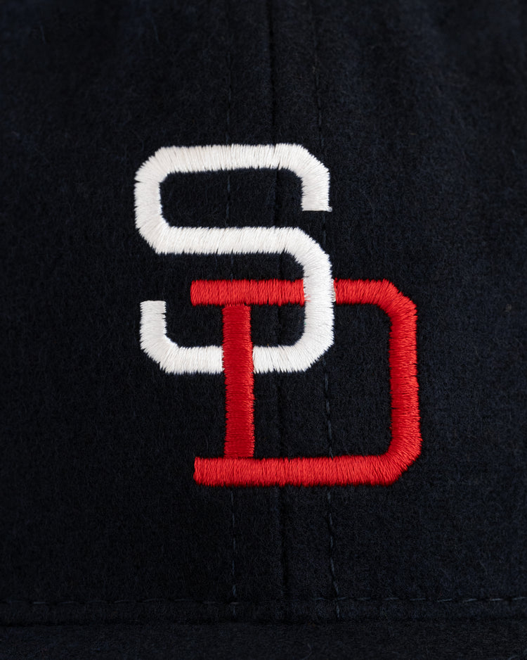 Close-up of EFF’s San Diego Padres (PCL) 1956 Authentic Wool Ballcap, featuring black fabric with interlocking white S and red D embroidery, reflecting the classic SD logo from the team’s Pacific Coast League era.