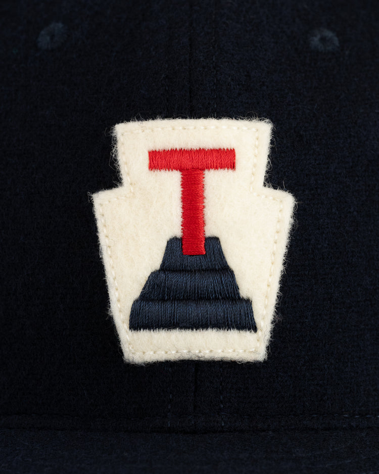 A close-up of the cream keystone patch with a red T and navy steps—iconic details from the EFF Tabasco Plataneros 1964 Authentic Wool Ballcap.