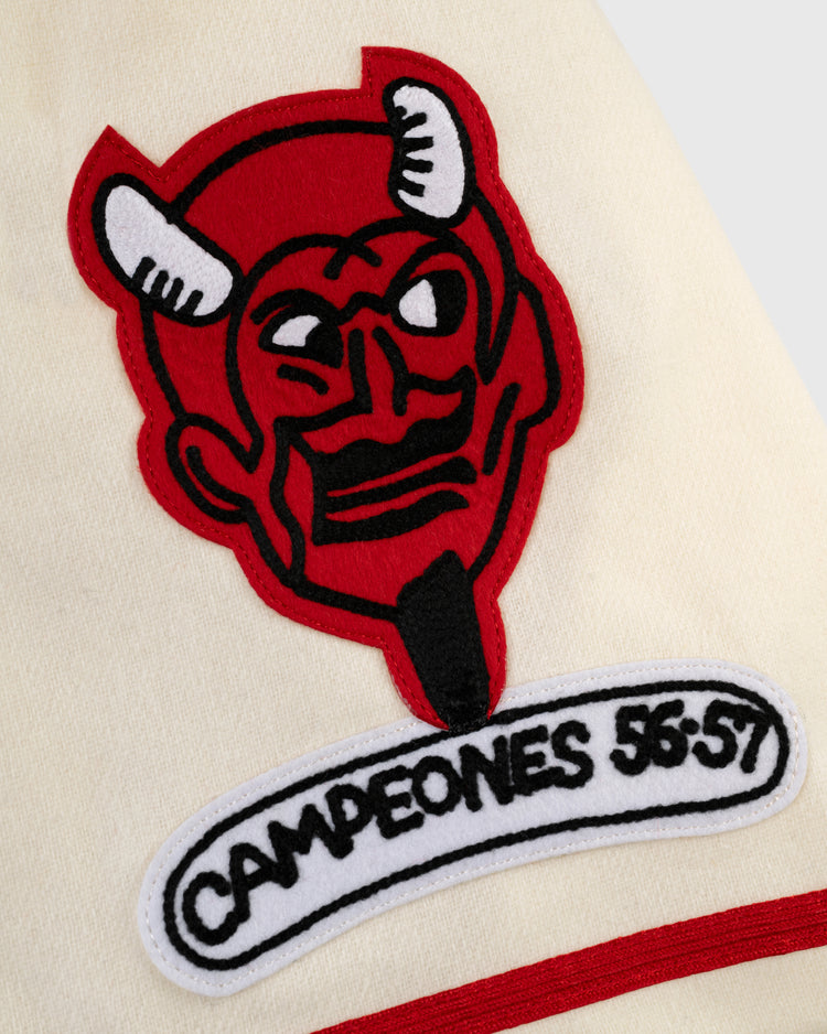 An embroidered red devil head with white horns sits above a
