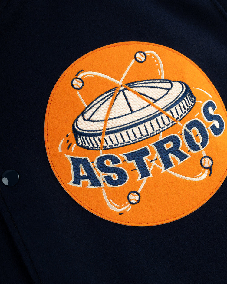 A close-up of the ASTROS patch with a stylized dome and baseballs, inspired by the 1965 Astrodome, on orange wool from the EFF Houston Astros 1965 Authentic All Wool Varsity Jacket.