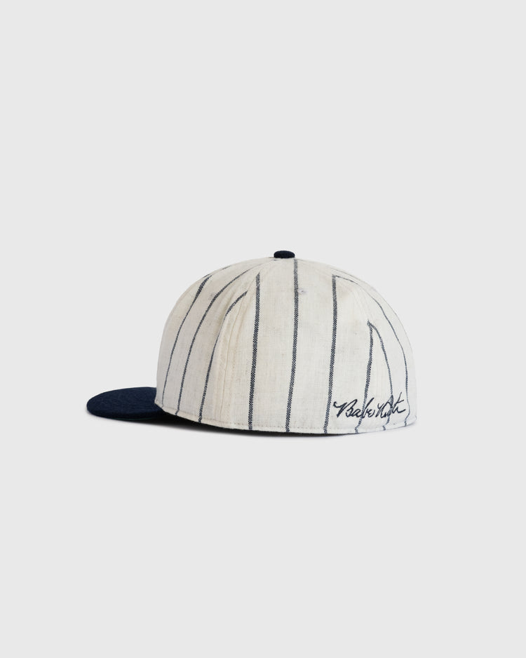 The Babe Ruth 1932 Signature Series Wool Ballcap by Ebbets Field Flannels features a white design with thin black pinstripes, a navy brim, and black cursive embroidery—an iconic piece of baseball memorabilia shown on a simple backdrop.