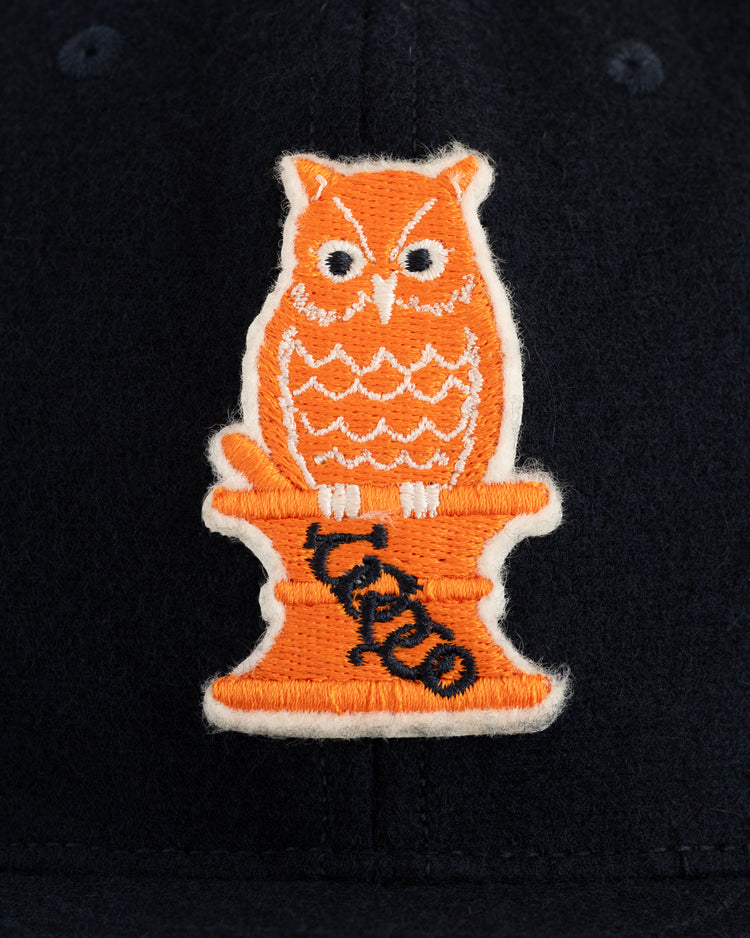 An orange 1941 Owl logo is embroidered on an orange pedestal with OCTOBERS VERY OWN vertically, featured on EFFs Owl Drug 1941 Authentic Wool Ballcap against a dark fabric background.