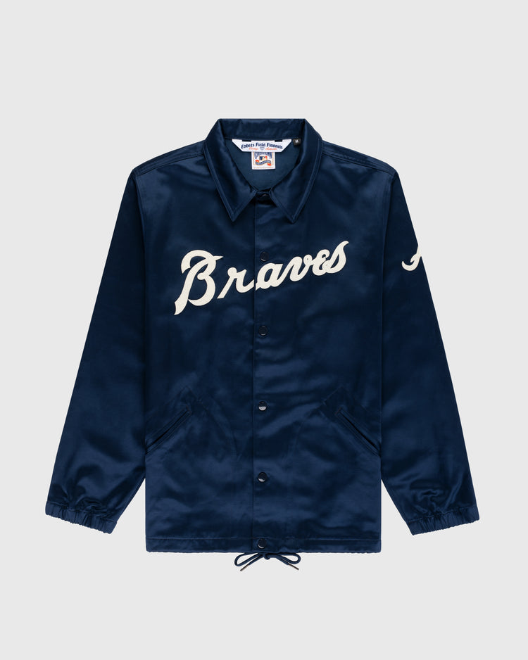 The EFF Atlanta Braves 1968 Satin Windbreaker Jacket is navy blue with “Braves” in white script, a “J” on the left sleeve, collar, snap buttons, front pockets, drawstring hem, and features the classic 1968 Braves logo.