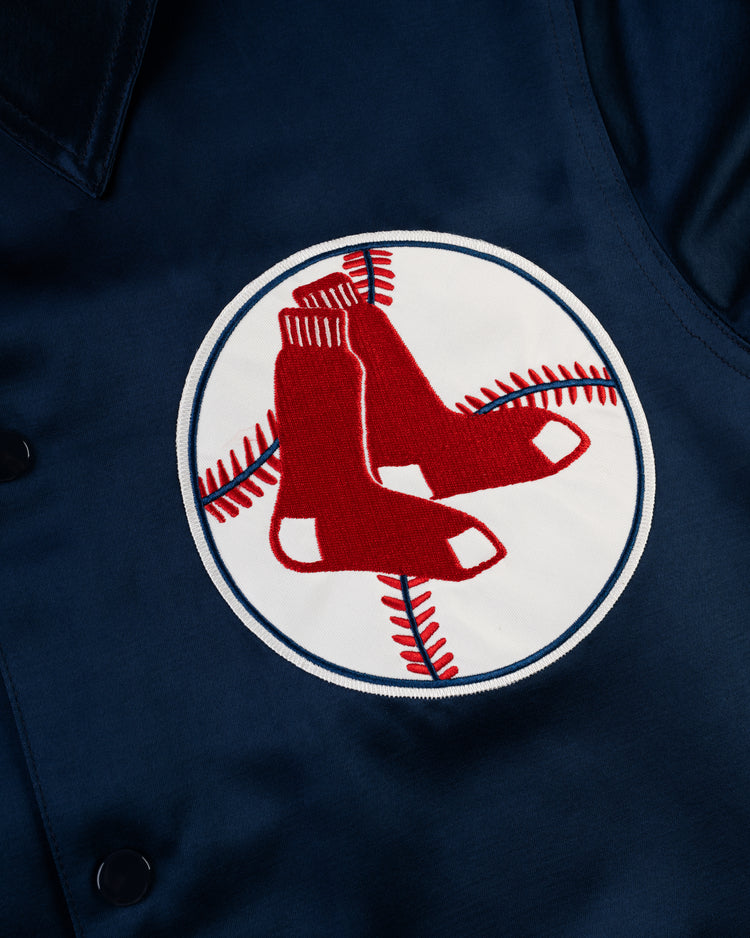 Close-up of the EFF Boston Red Sox 1967 Satin Windbreaker Jacket, styled vintage with a circular patch showing two red socks over a white background with red baseball stitching—the iconic team logo.