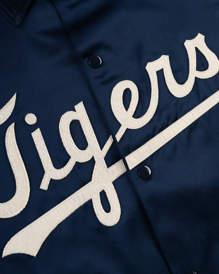 Close-up of the EFF Detroit Tigers 1960 Satin Windbreaker Jacket in navy blue, featuring large white stitched cursive Tigers lettering on the front and black snap buttons.