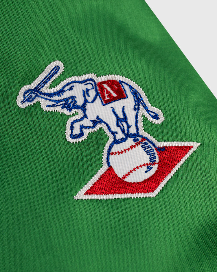 The EFF Kansas City Athletics 1963 Satin Windbreaker Jacket features a white elephant with a raised trunk on a baseball atop a red base-shaped patch, embroidered on green fabric; the elephant sports a red blanket with a white âA.â.