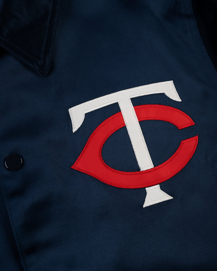 A close-up of the EFF Minnesota Twins 1966 Satin Windbreaker Jacket in navy blue, featuring the classic white T over red C team logo on the front, inspired by vintage MLB styles.