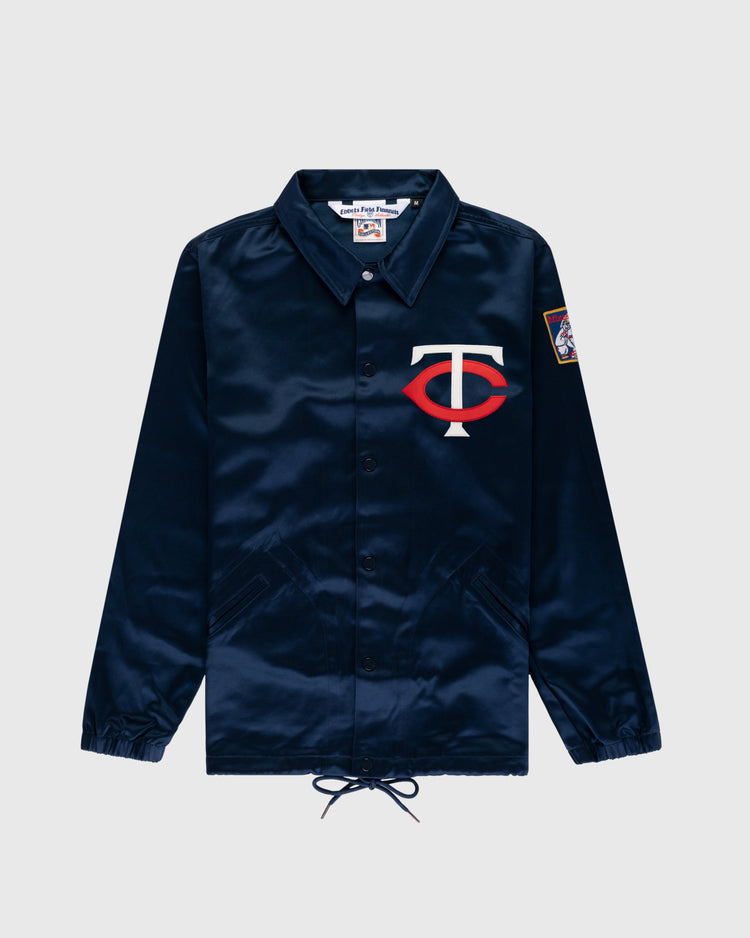 The EFF Minnesota Twins 1966 Satin Windbreaker Jacket is navy blue with a white and red TC logo on the left chest and a colorful patch on the right sleeve, shown against a light gray background.