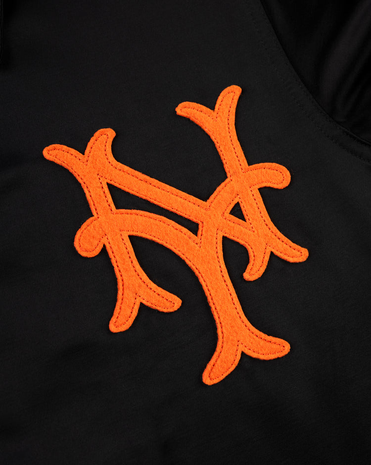 Close-up of an orange, stylized NY logo stitched on black fabric of the EFF New York Giants 1954 Satin Windbreaker Jacket, evoking classic MLB style and vintage team spirit.