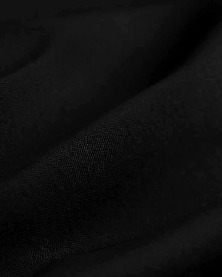 Close-up of the black fabric on the EFF New York Giants 1954 Satin Windbreaker Jacket, featuring soft folds and subtle texture that evoke an authentic satin feel, with gentle shadows and highlights across the surface.