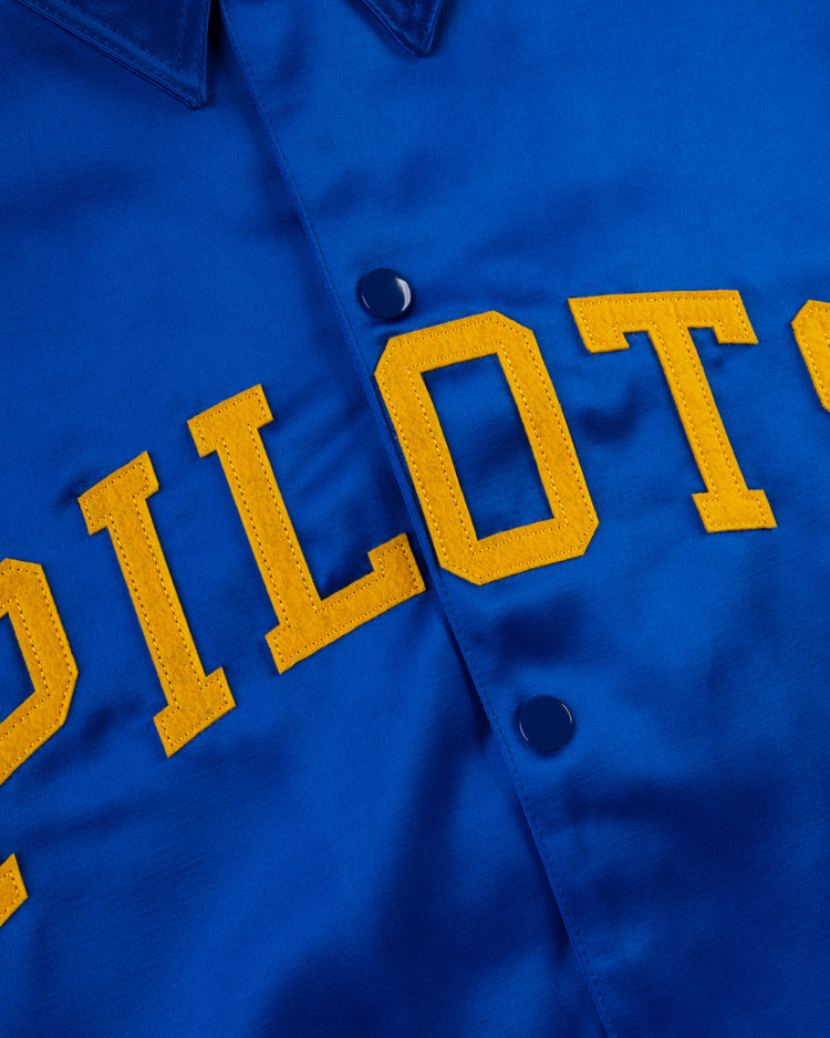 Close-up of the EFF Seattle Pilots 1969 Satin Windbreaker Jacket, featuring yellow PILOTS lettering and blue snap buttons, showcasing detailed stitching and the rich satin fabric texture.