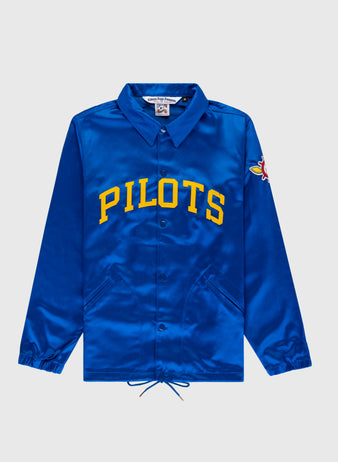 The EFF Seattle Pilots 1969 Satin Windbreaker Jacket features royal blue satin, yellow PILOTS lettering, a colorful pilot patch on the sleeve, plus classic details like a collar, snap buttons, and drawstrings at the hem.