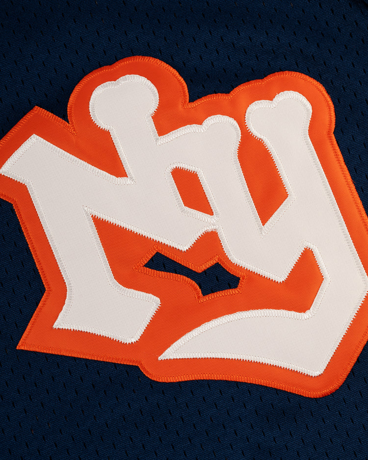 A close-up of the white NY logo with an orange outline on dark blue mesh, from the EFF New York Knights Mesh V-Neck Jersey—evoking classic vintage style.