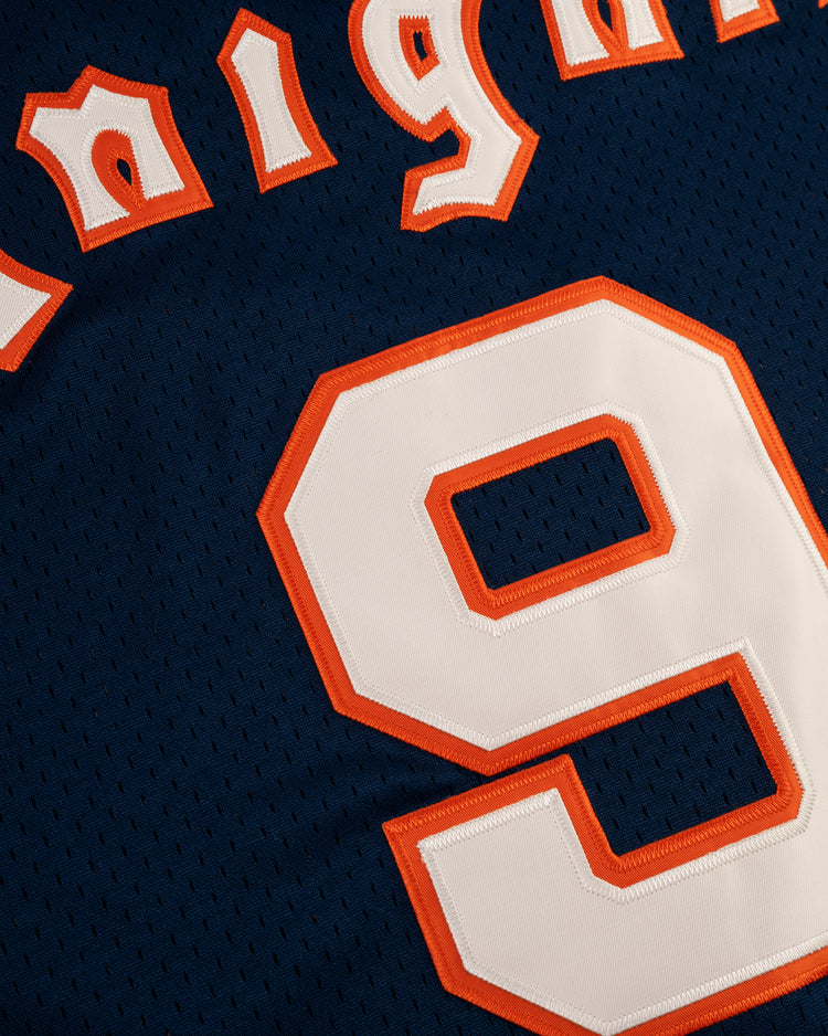 A close-up of the EFF New York Knights Mesh V-Neck Jersey in navy blue, featuring a vintage design with the white number 9 outlined in orange and partial orange and white lettering at the top.