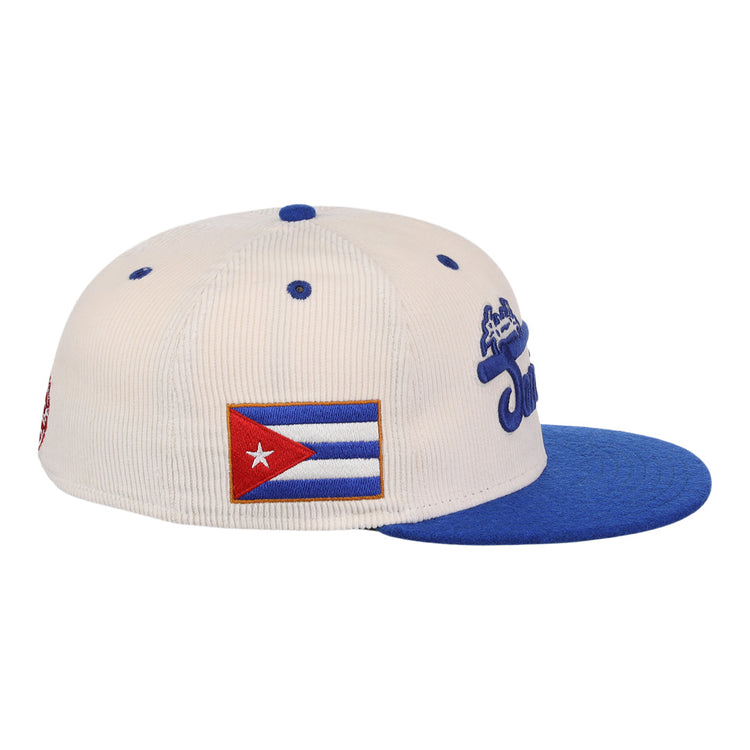 The Santurce Cangrejeros NLB Ground Rule Double Fitted Ballcap by EFF is a white vintage-inspired corduroy hat with a blue brim, embroidered Cuban flag patch on the side, and blue text on the front.