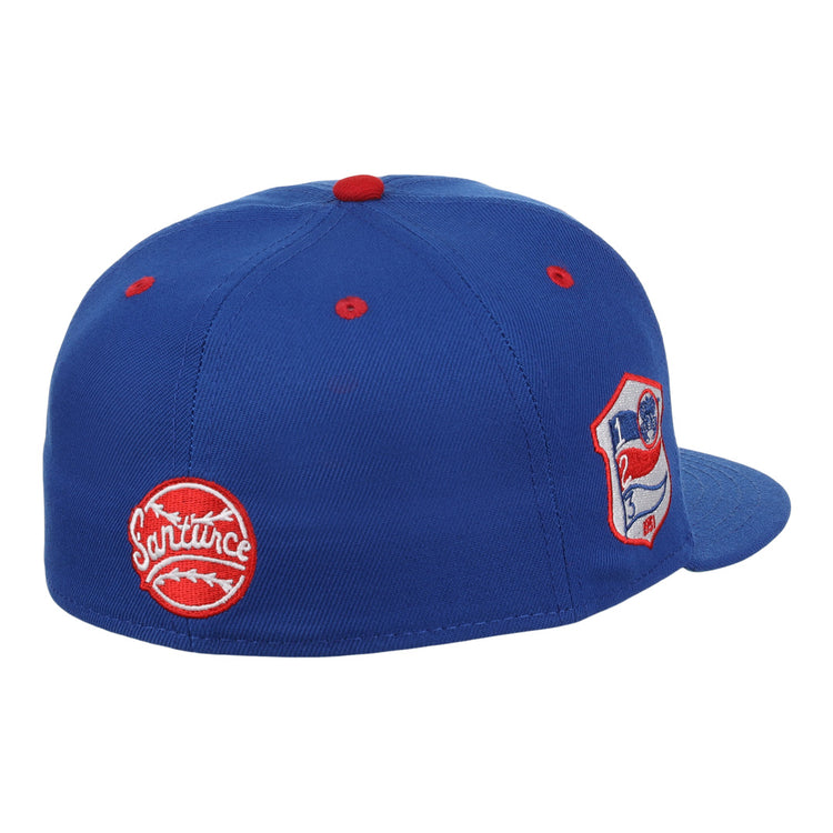 The EFF Santurce Cangrejeros NLB Team Color Fitted Ballcap is a vintage-inspired blue cap with red accents, featuring two embroidered patches: a round red Santurce logo and a shield patch with a flag and number 21 from the Puerto Rican League.