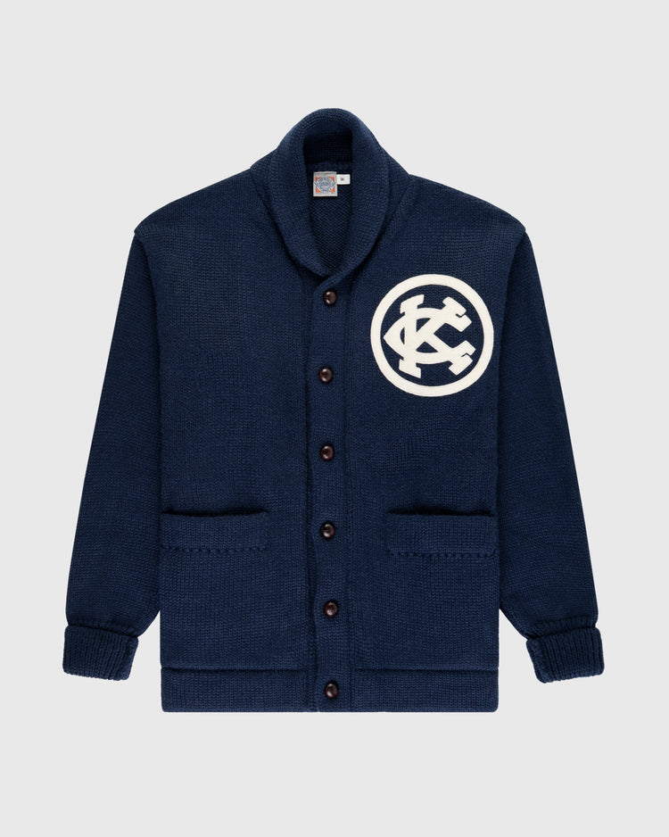 The EFF Kansas City Monarchs 1922 Wool Shawl Collar Sweater is a navy blue wool cardigan with brown buttons, two front pockets, and a white KC patch on the left chest, inspired by the historic Negro Leagues World Series era.