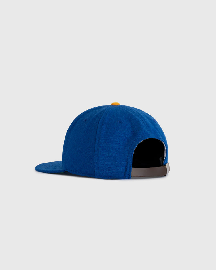 The EFF Chinese Athletic Club (Hawaii) 1910 Authentic Wool Ballcap is shown from the back in blue wool, featuring a yellow top button, brown adjustable strap, and a light gray background. Inspired by Hawaii baseball history.