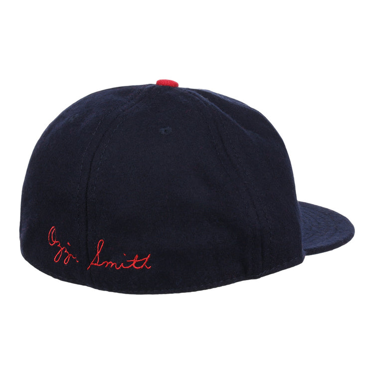 The Ozzie Smith Signature Series Ballcap by Ebbets Field Flannels is shown from the rear, featuring navy vintage wool, red Ozzie Smith stitching on the back, and a small red button on top.