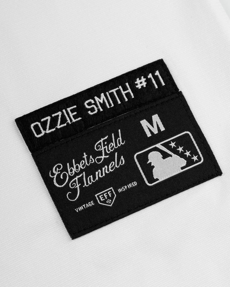 A close-up of a black patch on white fabric, reading Walla Walla Padres Mesh V-Neck Jersey, EFF, M, and featuring the MLB logo and Vintage Inspired—a classic nod to baseball heritage.