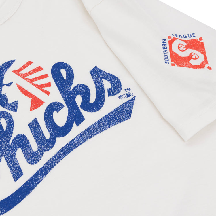The Ebbets Field Flannels Memphis Chicks EFF MiLB Vintage T-Shirt features bold blue “Chicks” text with red accents, a sleeve logo in red and blue, and is crafted from premium cotton for lasting comfort.