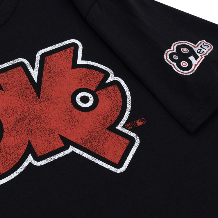 A close-up of the Ebbets Field Flannels Oklahoma City 89ers EFF MiLB Vintage T-Shirt in black premium cotton, with a large cracked-texture red and white chest graphic and a small “89ers” sleeve patch, inspired by Vintage Minor League tees.