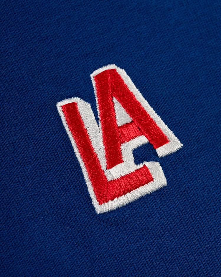 Red and white embroidered LA letters overlap on blue fabric, featuring the iconic 1942 Los Angeles Angels (PCL) logo—perfect on the Ebbets Field Los Angeles Angels (PCL) Embroidered ‘LA’ Short Sleeve Tee.