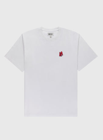 The Ebbets Field Los Angeles Angels (PCL) Embroidered ‘LA’ Short Sleeve Tee features a classic white design with a small red and black ‘LA’ logo on the left chest, laid flat on a light gray background, reflecting vintage-inspired style.